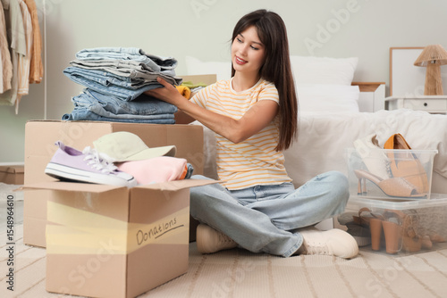 Young woman packing jeans f...