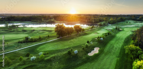 Golf course at sunset with beautiful sky and sand trap. Scenic panoramic view of golf fairway with bunker from drone © TTstudio