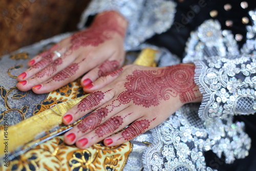 Photography henna tattoo being applied on a women's hand.