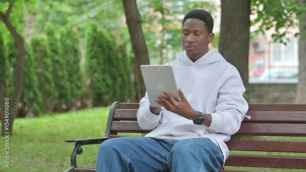 Young African Man Using a Digital Tablet Outdoor on Bench Young African Man Using a Digital Tablet Outdoor on Bench