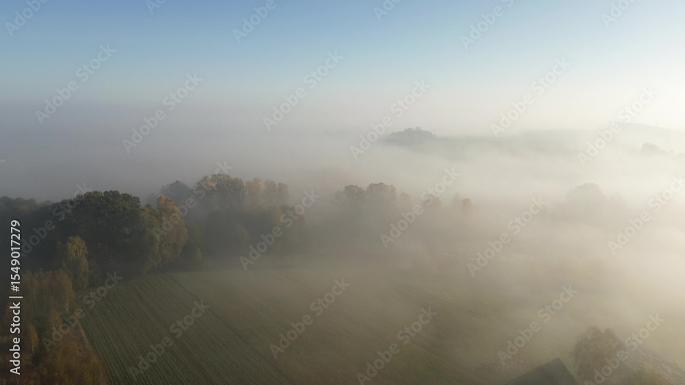 Fototapeta premium Sunrise fog over colorful autumn forest and fields