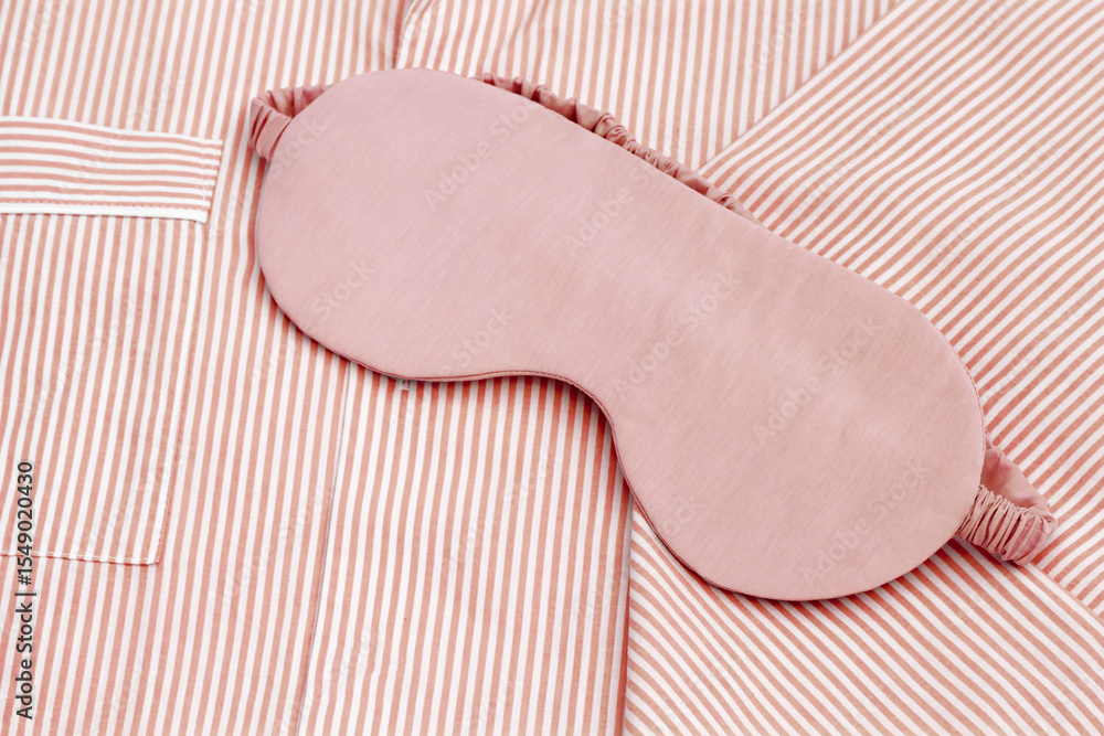 Fototapeta premium Pink eye mask for sleep on folder striped red pajama, close up texture fabric, minimal lifestyle aesthetic flat lay photo. Top view woman sleeping mask for comfort rest, healthy trend
