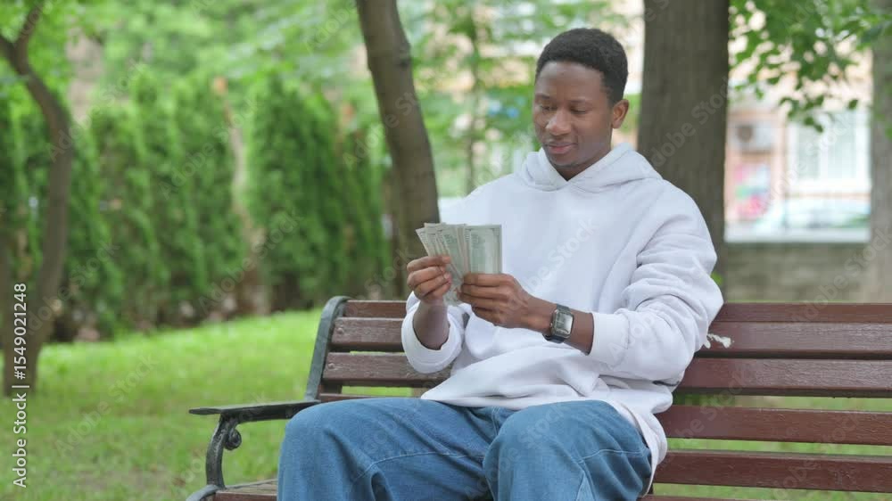Young African Man Happily Counting Money while Sitting Outdoor Young African Man Happily Counting Money while Sitting Outdoor