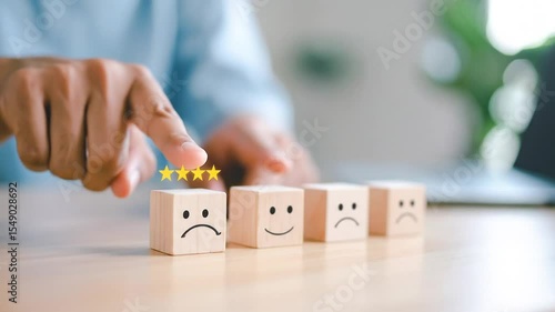 A hand selecting a five-star rating on small wooden blocks, each displaying a different emotional reaction