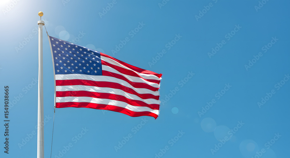 Obraz premium Side view of American flag waving in the wind against clear blue sky as a symbol of national unity