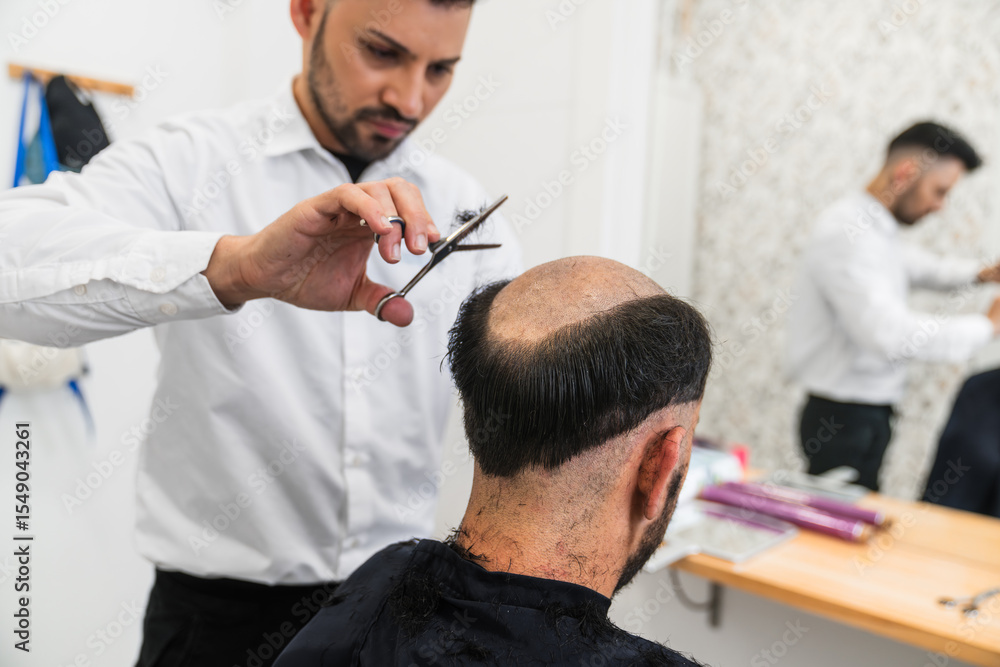 Fototapeta premium Hairdresser cutting remaining hair of customer in preparation for applying hair prosthesis in hair clinic