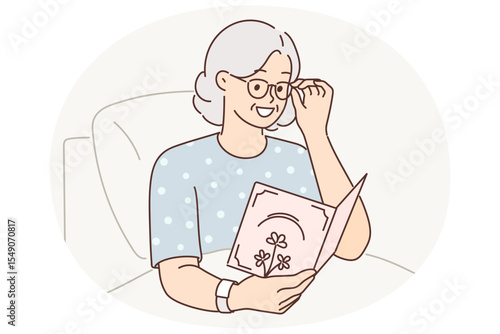 Sick elderly woman lying in hospital holds card from loved ones with wishes for speedy recovery