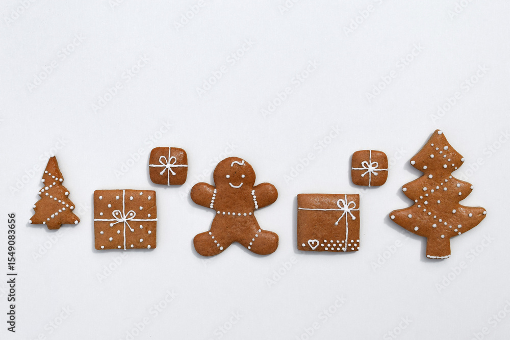 Fototapeta premium Decorated gingerbread cookies - trees, christmas presents and gingerbread man on a white background, copy space for text