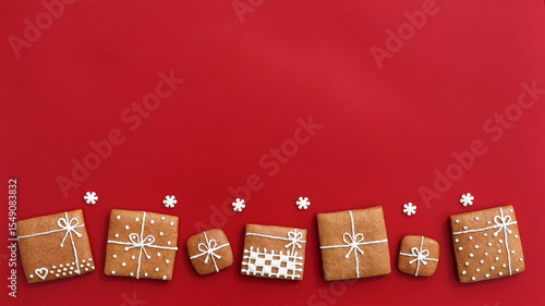 Decorated gingerbread cookies - christmas presents with small sugar snowflakes on a red background, copy space for text