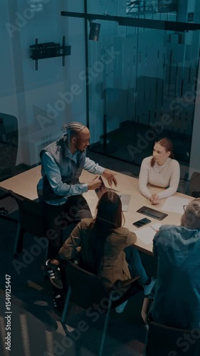 A diverse team of young professionals collaborates in a modern office conference room. Businesspeople discuss strategy, technology, and planning, using laptops to develop an innovative e-commerce
