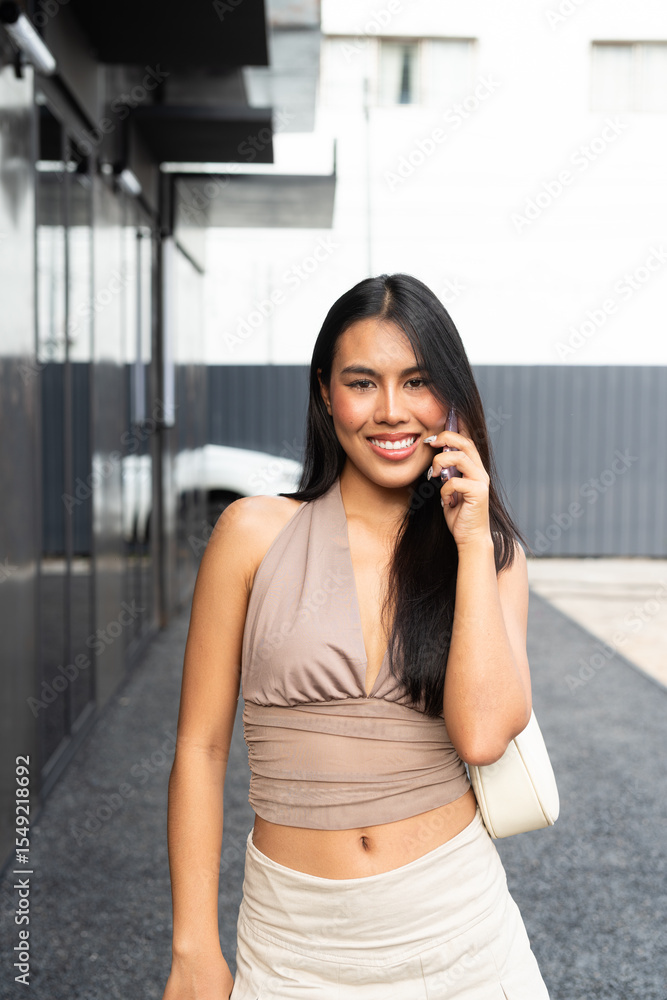 Fototapeta premium Modern Asian Woman Using Phone Outdoors in City