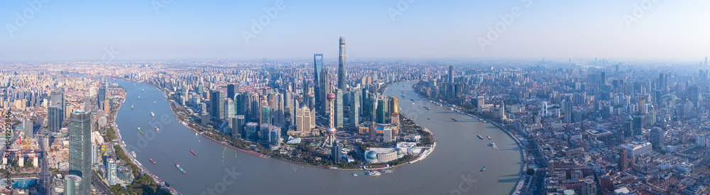 Fototapeta premium Aerial view of Shanghai skyscrapers in downtown with winding river on sunny day.