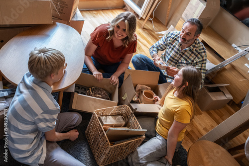 	
A family is moving into a new apartment, unpacking boxes together in the living room. They organize their belongings and start setting up their new home.	
