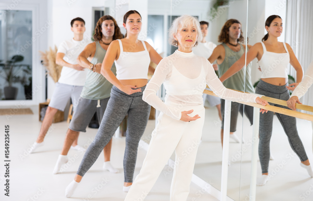 Fototapeta premium Group of people of different ages practice ballet moves in classical dance school.