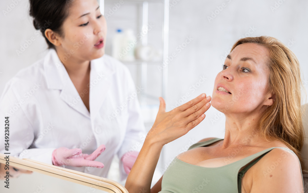 Woman beautician examining face skin of female patient before cosmetology procedure in beauty clinic Woman beautician examining face skin of female patient before cosmetology procedure in beauty clinic