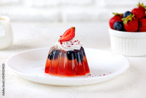 Jelly dessert with strawberry, blueberries, agar agar and coconut cream on light table. Vegan, sugar and lactose free.