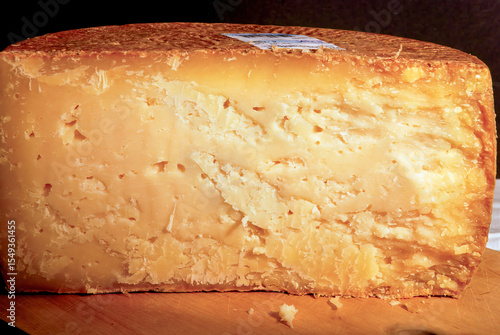 Cut wheel of seasoned cheese resting on wooden cutting board