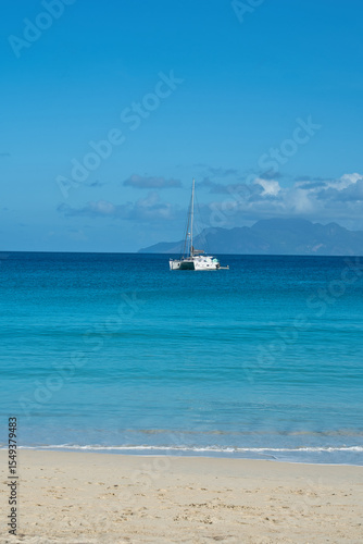 Beautiful beach of Beau Vallon, docking yacht, transparent and turquoise water, with silhouette island at the back, Mahe, Seychelles 