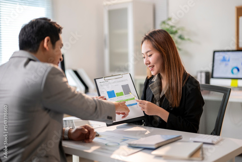 Wallpaper Mural A man and a woman are sitting at a desk with a presentation in front of them Torontodigital.ca