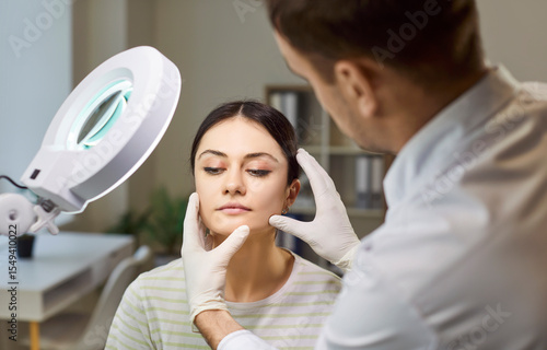 Cuadro en lienzo Dermatologist doctor looking closely at woman face skin doing examination with d