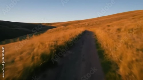 Winding Dirt Path in Golden Hills – Aerial Sunset Landscape