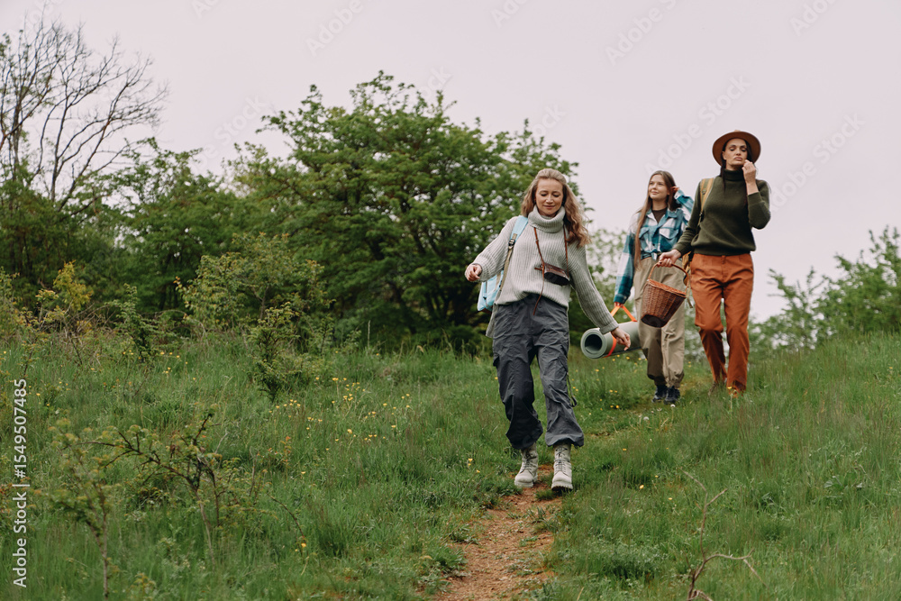 Obraz premium Active middle age woman hiking outdoors with friends in green nature, enjoying wellness, fitness, and healthy lifestyle in community setting during spring season.