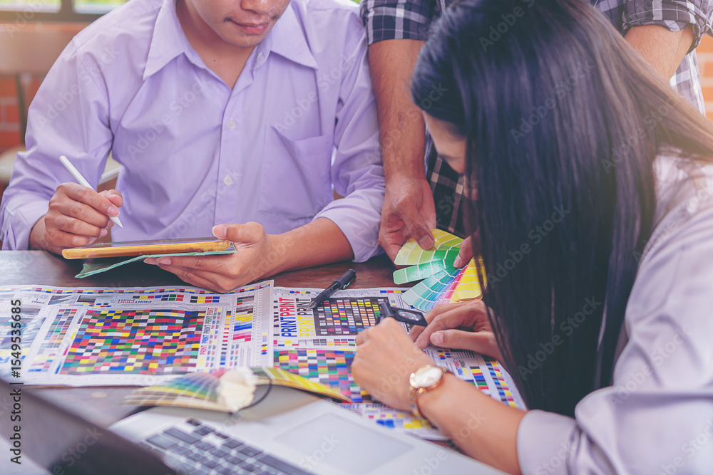Fototapeta premium Team graphic designer checking print quality of media graphics proof print and color guides in printing industry. Selected focus