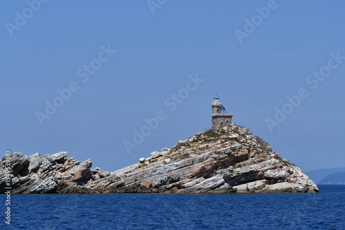Scenic Lighthouse on Rocky Island Surrounded by Clear Blue Water
