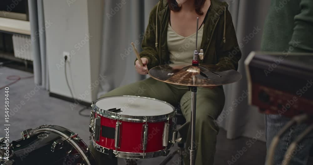 A female drummer practices with her band before a concert. The band is getting ready and preparing their instruments. A female drummer practices with her band before a concert. The band is getting ready and preparing their instruments.