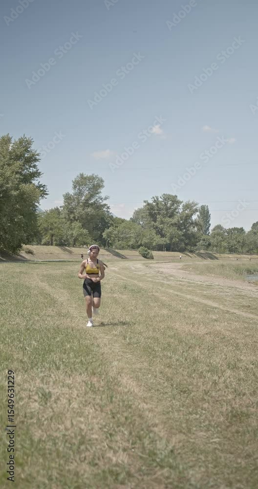 Young Asian woman enjoys a morning jog by the river in the park. She's wearing a yellow top, black shorts, and white sneakers. Healthy lifestyle. Young Asian woman enjoys a morning jog by the river in the park. She's wearing a yellow top, black shorts, and white sneakers. Healthy lifestyle.