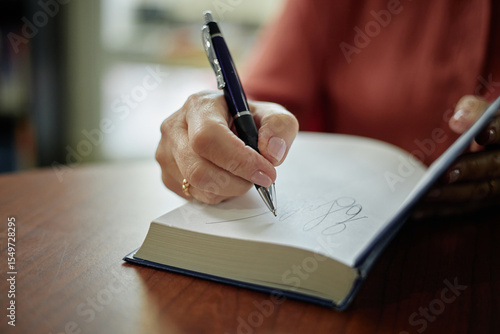 Quadro su tela Hands of female author signing book with pen, close up of writing autograph on b