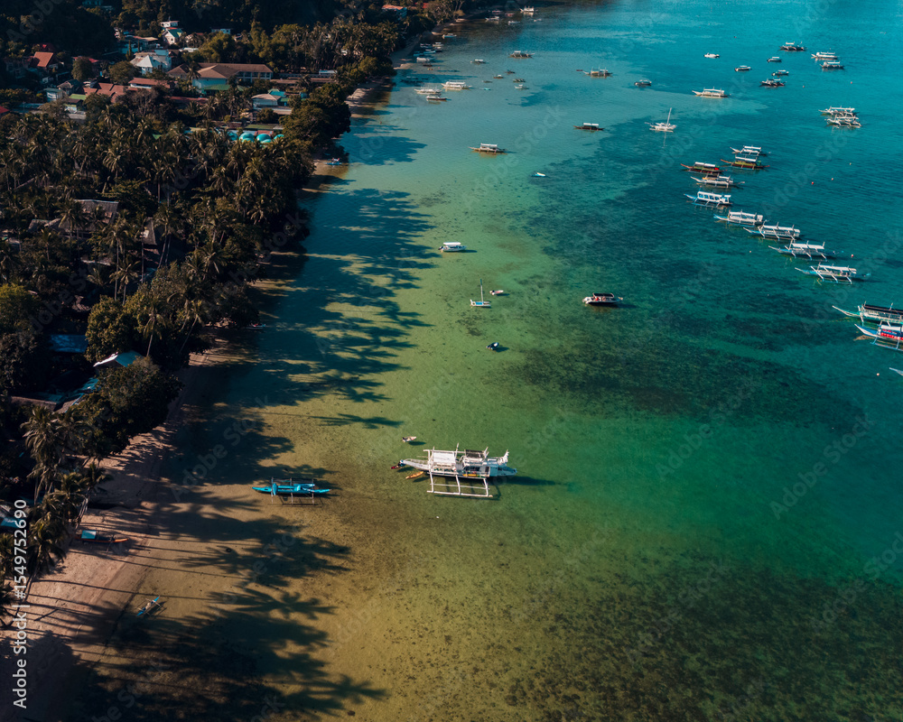 Obraz premium Bangka boats resting in Clear Skies and Peaceful Blue Horizon Over Coastal Paradise of El Nido’s Corong Corong Beach