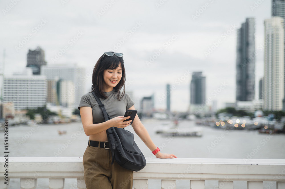 Happy young southeast asian woman teenager blogger searching map guide smartphone. World travel explorer local cultural experience tourism concept Bangkok Thailand near Chao Phraya River Asia Happy young southeast asian woman teenager blogger searching map guide smartphone. World travel explorer local cultural experience tourism concept Bangkok Thailand near Chao Phraya River Asia