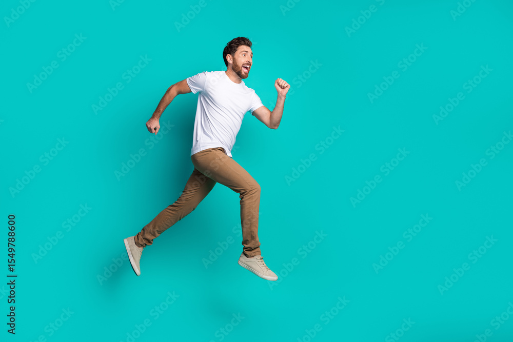 Energetic young man leaping joyfully in casual attire against a vibrant teal background with a confident expression Energetic young man leaping joyfully in casual attire against a vibrant teal background with a confident expression