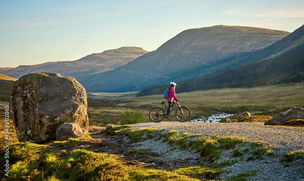 Fototapeta premium active woman riding her electric mountain bike along the awesome fairy pools on the Isle of Skye in Scotland, UK
