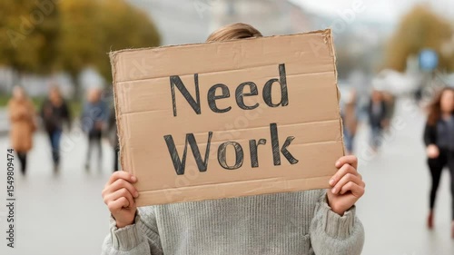 Wallpaper Mural Urban scene: person holding "need work" sign amidst diverse crowd movement Torontodigital.ca