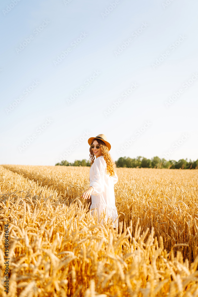 Young woman enjoying sunny day walking in golden wheat field. Beautiful woman in white dress and hat walking in field, feeling pleasure. Walking, nature concept. Young woman enjoying sunny day walking in golden wheat field. Beautiful woman in white dress and hat walking in field, feeling pleasure. Walking, nature concept.