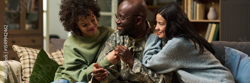 Foto Middle aged Black man in military uniform sitting on couch embracing smiling tee