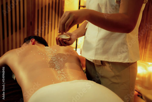 Obraz na plátně Man customer having exfoliation treatment in luxury spa salon with warmth candle light ambient