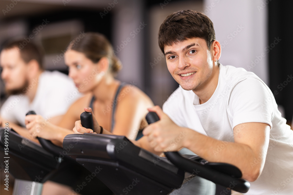 Young motivated guy training on an exercise bike in the gym Young motivated guy training on an exercise bike in the gym