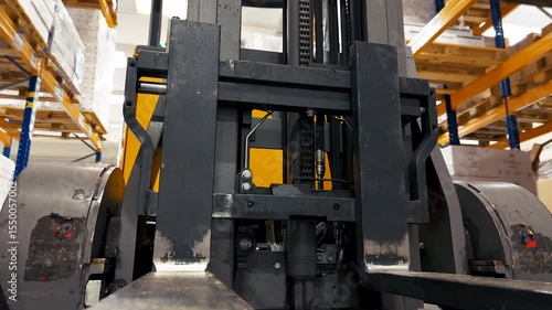Static shot of a modern moving forklift truck in a warehouse with goods on shelves. Mechanized transportation and loading and unloading cargo. View from below. No people.