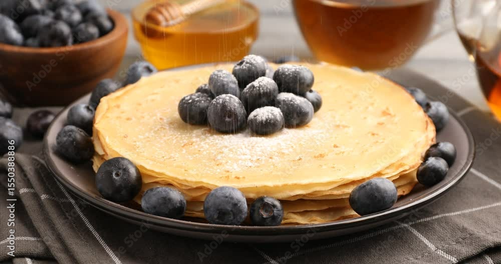 Sieving sugar powder onto delicious crepes at table, closeup Sieving sugar powder onto delicious crepes at table, closeup