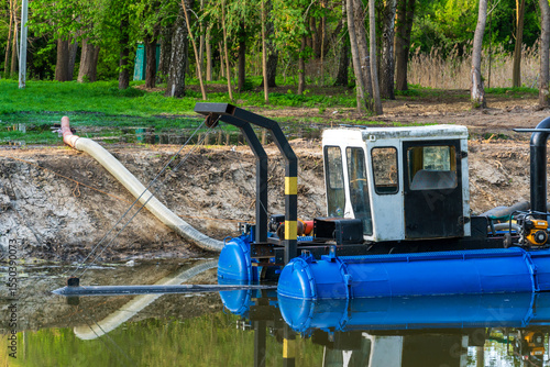 Slika na platnu Dredging Machine Floating on Water Extracting Silt from Lake Bed with Woods in B