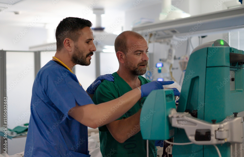 Two doctors discussing medical equipment settings in hospital room Two doctors discussing medical equipment settings in hospital room