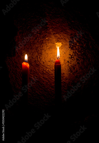 Dos velas rojas encendidas sobre fondo rústico oscuro, simbolismo espiritual e iluminación cálida