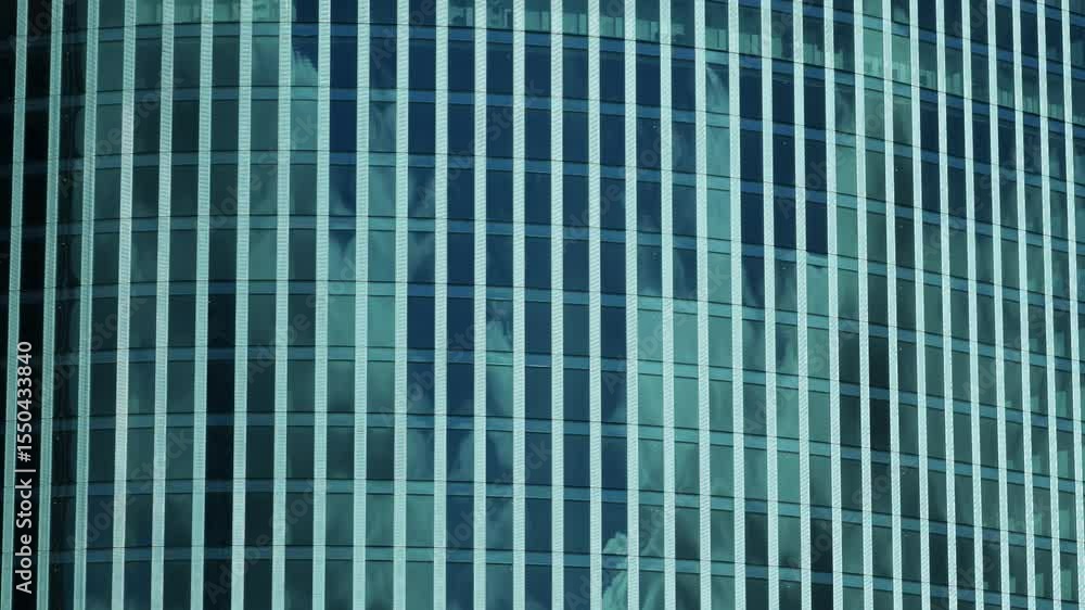 Modern glass skyscraper reflecting clouds in windows forming repeating geometric pattern Modern glass skyscraper reflecting clouds in windows forming repeating geometric pattern