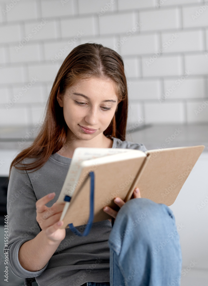 Sweet Teen Girl Reading Notebook Entries While Sitting On A Chair At Home Sweet Teen Girl Reading Notebook Entries While Sitting On A Chair At Home