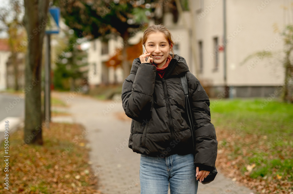 Happy Girl Talking On The Phone Against A Blurred Street Background Happy Girl Talking On The Phone Against A Blurred Street Background