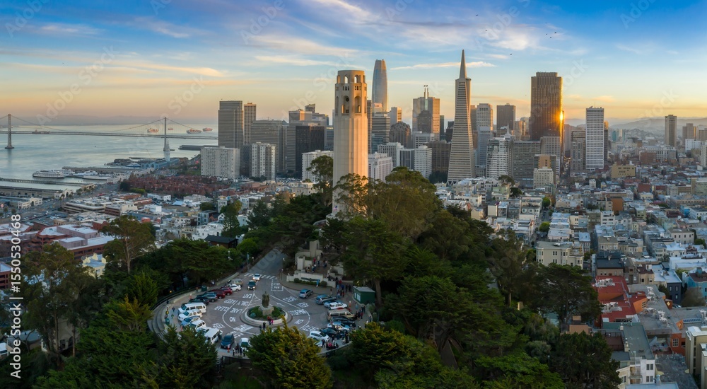 Obraz premium An aerial view of Coit Tower and the San Francisco skyline, including the Transamerica Pyramid, at sunset in California, USA. Tourists visit the landmark.