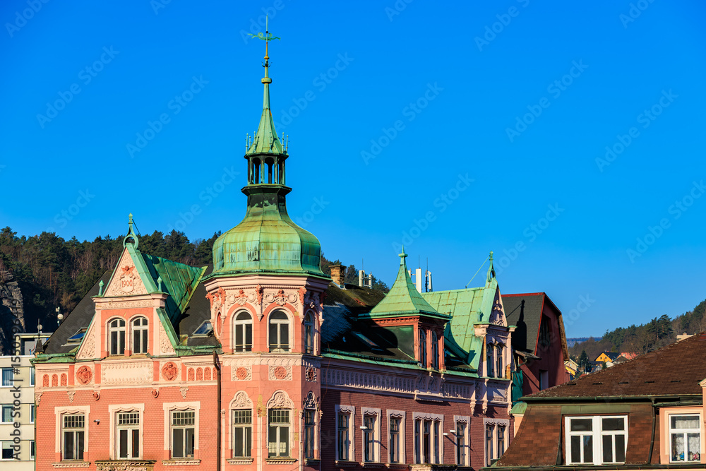 Fototapeta premium Historic pink castle-like building with green roof against clear blue sky